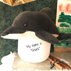 Pic of stuffed dolphin named "Shark" in Elaina's studio atop a crystal bowl